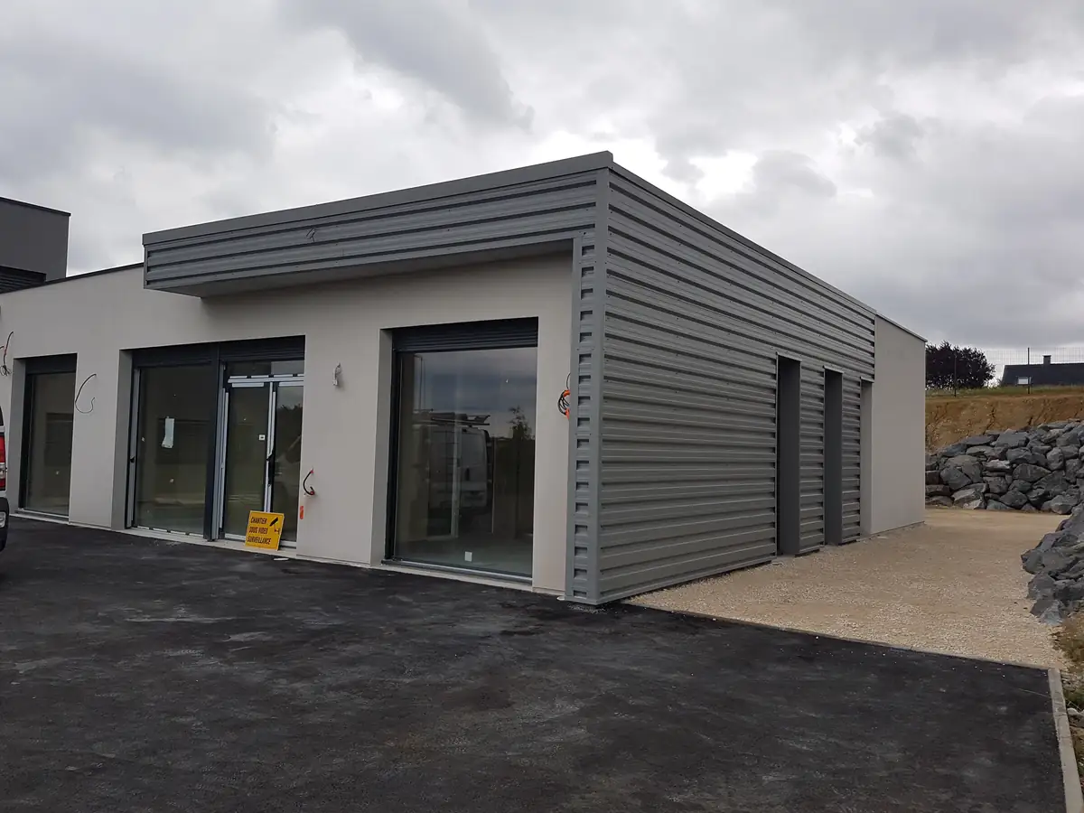 Showroom avec bardage métallique gris et enduit blanc